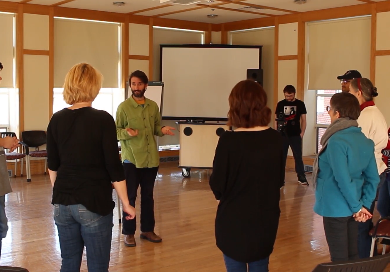 A group of people standing in a circle talking in a workshop